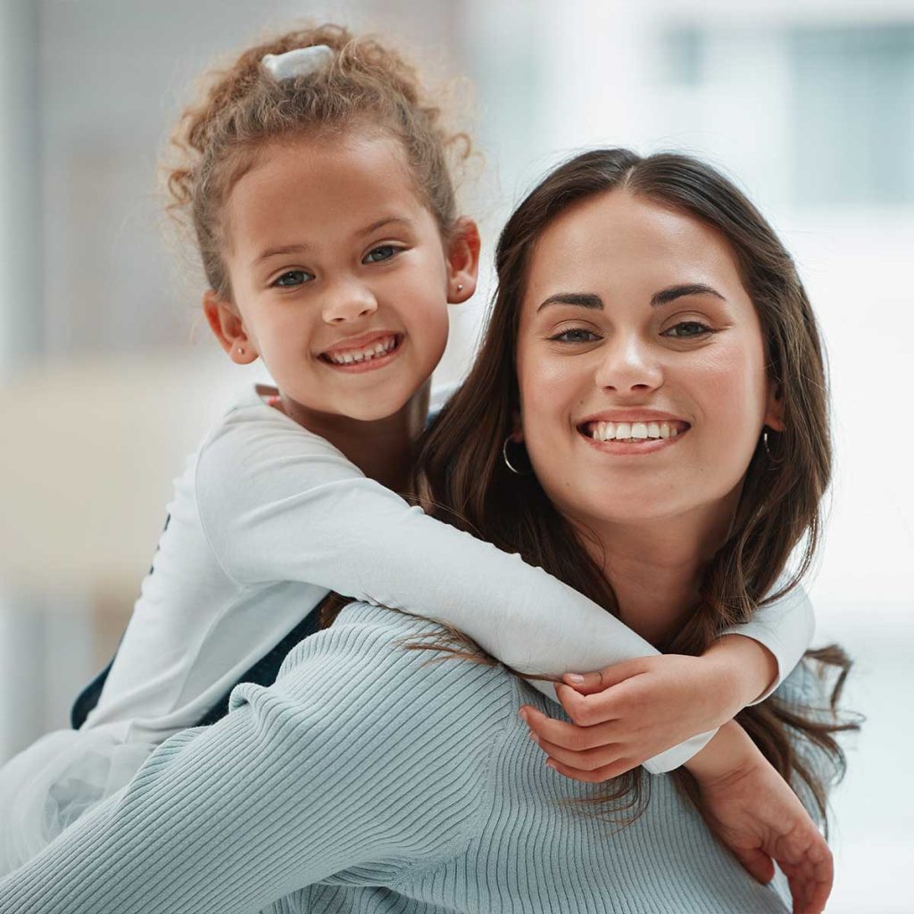 Teenage girl carrying her little sister on her back.